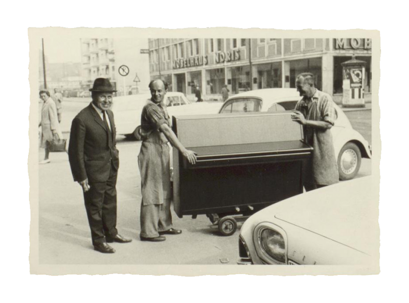 Geschäftsführender Verkäufer Görl (links) mit den Schreinern Pre und Präger des Pianohaus Rück, nach 1965